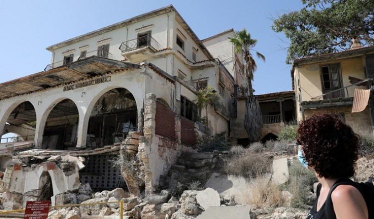 Γυναίκα στέκεται μπροστά από μισοκατεστραμμένο κτήριο στο κέντρο των Βαρωσίων στην Κύπρο (φωτ. αρχείου: EPA / Κάτια Χριστοδούλου)