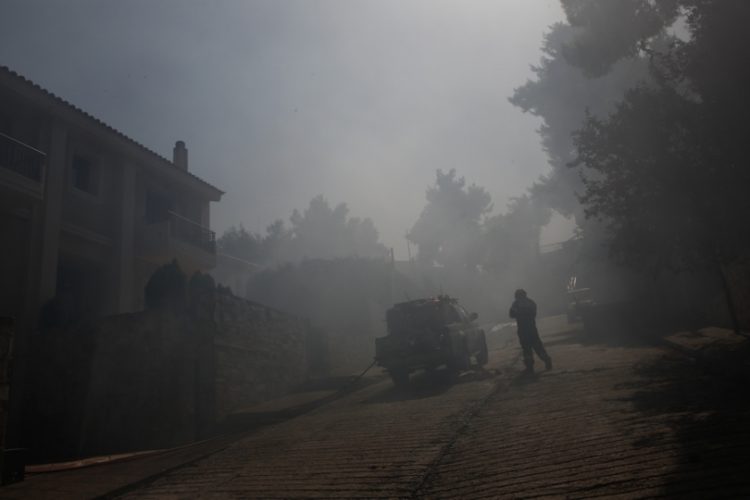 Πυροσβέστης μέσα σε κατοικημένη περιοχή επιχειρεί στην κατάσβεση της πυρκαγιάς που ξέσπασε σε δασική περιοχή στη Σταμάτα, Αττικής (φωτ.: ΑΠΕ-ΜΠΕ / Γιάννης Κολεσίδης)