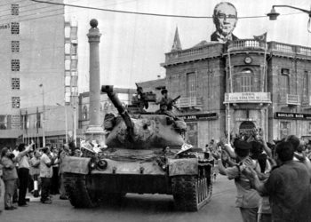 24 Ιουλίου 1974. Ένα τουρκικό τανκ περνάει μπροστά απ’ το Saray Hotel στο κατεχόμενο μέρος της Λευκωσίας. Στην οροφή του διπλανού κτηρίου διακρίνεται πανό με τον Μουσταφά Κεμάλ (φωτ.: αρχείο Associated Press)