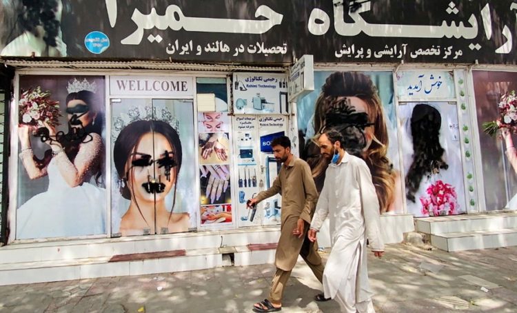 Αφγανοί περνούν μπροστά από σαλόνι ομορφιάς, στην Καμπούλ, όπου τα πρόσωπα των μοντέλων στις αφίσες έχουν παραμορφωθεί (φωτ.: EPA/STRINGER)