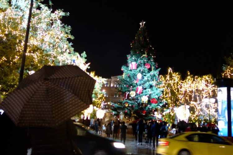 Εικόνα από την Πλατεία Συντάγματος όπου, την Τρίτη το βράδυ, έγινε η φωταγώγηση του χριστουγεννιάτικου δέντρου παρουσία πολιτών που έμειναν εκεί παρά τη βροχή (φωτ.: Γιώργος Κονταρίνης/ EUROKNISSI)