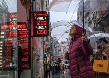 Περαστικοί βλέπουν τις ισοτιμίες της τουρκικής λίρας με το ευρώ και το δολάριο, σε κατάστημα συναλλάγματος στην Κωνσταντινούπολη (φωτ.: EPA/SEDAT SUNA)