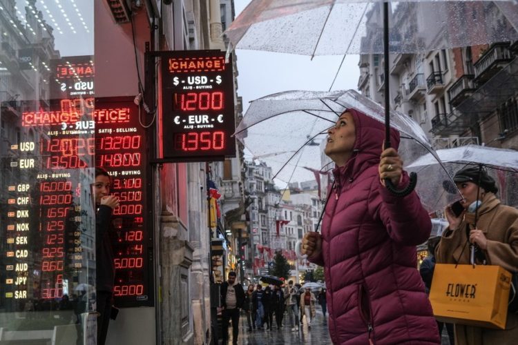 Περαστικοί βλέπουν τις ισοτιμίες της τουρκικής λίρας με το ευρώ και το δολάριο, σε κατάστημα συναλλάγματος στην Κωνσταντινούπολη (φωτ.: EPA/SEDAT SUNA)