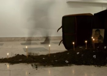 Εγκατάσταση χώμα, βαλίτσα, κεριά, εικόνα, γραμματόσημα, διαστάσεις μεταβλητές. Το 2019 στο Ελληνικό Γενικό Προξενείο της Νέας Υόρκης. Έργο και φωτογραφία του Γιώργου Ταξίδη