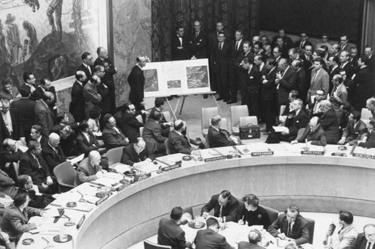 O Αμερικανός πρεσβευτής Αντλέ Στίβενσον ΙΙ στον ΟΗΕ δείχνει αεροφωτογραφίες ρωσικών πυραύλων στην Κούβα, κατά τη διάρκεια συνεδρίασης του Συμβουλίου Ασφαλείας του ΟΗΕ, στις 25 Οκτωβρίου 1962, παρουσία του τότε πρεσβευτή της Ρωσίας Βαλέριαν Ζόριν (φωτ.: en.wikipedia.org)