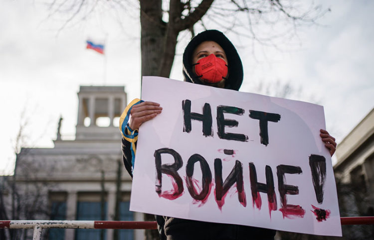 Διαδηλώτρια έξω από την πρεσβεία της Ρωσίας στο Βερολίνο. «Όχι στον πόλεμο» γράφει το πλακάτ που κρατάει (φωτ.: EPA / Clemens Bilan)