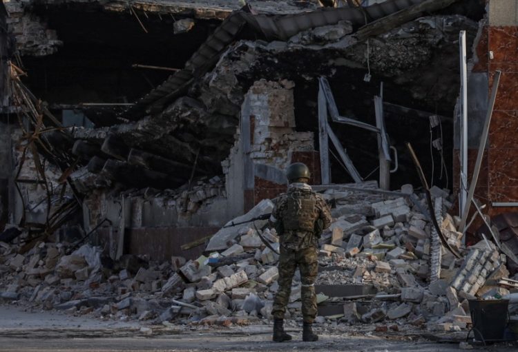 Ρώσος στρατιώτης μπροστά από τα ερείπια ενός καταστήματος στο κέντρο της Βολνοβάχα, στο Ντονέτσκ (φωτ.: EPA/SERGEI ILNITSKY)