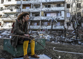 Γυναίκα στέκεται έξω από βομβαρδισμένο κτήριο στο Κίεβο (φωτ.: EPA / Miguel A. Lopes)