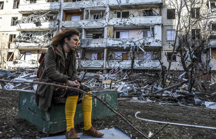 Γυναίκα στέκεται έξω από βομβαρδισμένο κτήριο στο Κίεβο (φωτ.: EPA / Miguel A. Lopes)