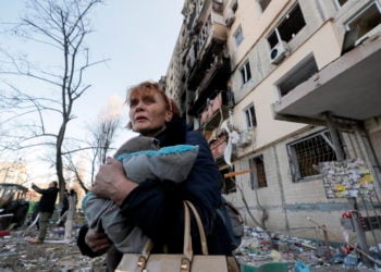 Μία γυναίκα κρατάει τις γάτες της φεύγοντας από το κατεστραμμένο σπίτι της (φωτ.: EPA/ Sergey Dolzhenko)
