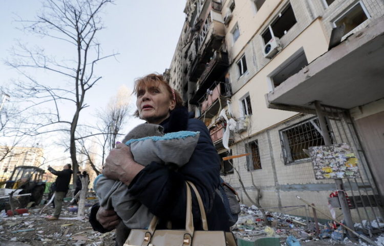 Μία γυναίκα κρατάει τις γάτες της φεύγοντας από το κατεστραμμένο σπίτι της (φωτ.: EPA/ Sergey Dolzhenko)
