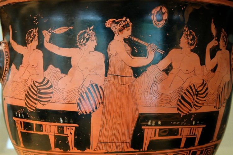 Σκηνή από συμπόσιο. Οι συνδαιτημόνες παίζουν κότταβο ενώ μία κοπέλα παίζει αυλό. Αττικός ερυθρόμορφος κρατήρας, Εθνικό Αρχαιολογικό Μουσείο της Μαδρίτης, 420 π.Χ. περίπου (πηγή: el.wikipedia.org)