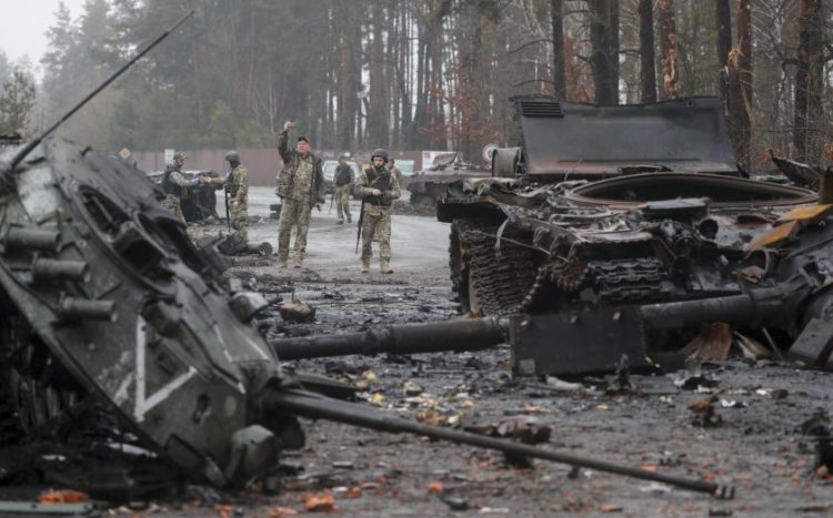 Ουκρανοί στρατιώτες περπατούν ανάμεσα σε κατεστραμμένα ρωσικά άρματα, σε περιοχή που ανακατέλαβαν, πλησίον του Κιέβου (EPA/ SERGEY DOLZHENKO)