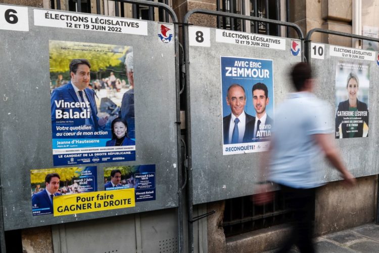 Ένας άνδρας περπατά μπροστά από αφίσες υποψηφίων των βουλευτικών εκλογών, σε περιοχή του Παρισιού (φωτ.: ΕΡΑ/ Mohammed Barda)
