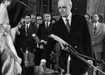 Κυβέρνηση Εθνικής Ενότητας. Ο Κωνσταντίνος Καραμανλής ορκίζεται πρωθυπουργός από τον Αρχιεπίσκοπο Σεραφείμ, 24 Ιουλίου 1974 (πηγή: Αρχείο ΕΡΤ / Συλλογή Αρ. Σαρρηκώστα)