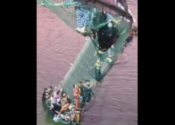 Άνθρωποι προσπαθούν να κρατηθούν στην πεζογέφυρα του ποταμού Ματσού στην Ινδία που έχει καταρρεύσει (Φωτ.: twitter.com/BNONews)
