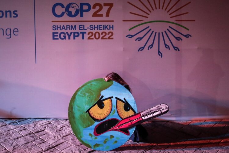 Ακτιβίστρια στη Διάσκεψη των Ηνωμένων Εθνών για το Κλίμα (COP27),  που γίνεται στο Σαρμ ελ Σέιχ της Αιγύπτου  κρατά κατασκευή που δείχνει τη γη να έχει πυρετό (Φωτ.: EPA/Sedat Suna)