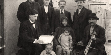 Ο Δ. Κουτσογιαννόπουλος (καθιστός, αριστερά) στη Δραπετσώνα, το 1921, καταγράφει ποντιακά τραγούδια από πρόσφυγες (φωτ.: αρχείο Κατερίνας Κουτσογιαννοπούλου)