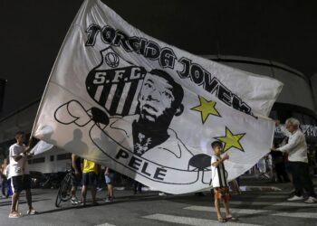 Οπαδοί της Σάντος κρατούν σημαία με τον Πελέ, έξω από το γήπεδο της ομάδας, αποτίοντας φόρο τιμής στον «βασιλιά» του ποδοσφαίρου που έφυγε από τη ζωή, Βραζιλία. (Φωτ.: EPA/Guilherme Dionizio)