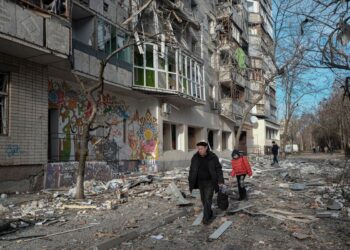 Ουκρανοί προσπερνούν κατεστραμμένο κτίριο κατοικιών μετά από ολονύχτιες ρίψεις ρουκετών στη Χερσώνα (φωτ. EPA/Maria Senovilla)