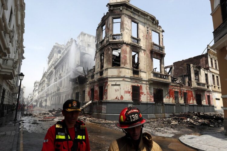 Πυροσβέστες έξω από τα ερείπια κτηρίου, το οποίο είχε ανακηρυχθεί Μνημείο Πολιτιστικής Κληρονομιάς, στην πρωτεύουσα του Περού, Λίμα, μετά από πυρκαγιά που προκάλεσαν οι διαδηλωτές (φωτ.: EPA/Paolo Aguilar)
