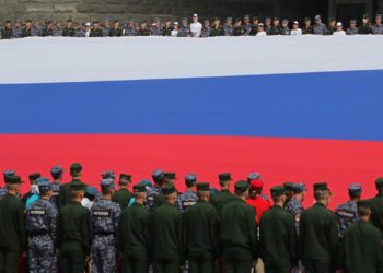 Ρώσοι στρατιώτες κρατούν μια τεράστια σημαία της Ρωσίας, στη διάρκεια εθνικής επετείου. Σύμφωνα με τις εκτιμήσεις του BBC, στη διάρκεια της εισβολής στην Ουκρανία, η Ρωσία θα μπορούσε να έχει περισσότερους από 24.000 νεκρούς (φωτ.: EPA/Maxim Shipenkov)