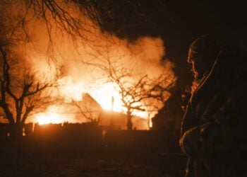 Γυναίκα κοιτάζει φλεγόμενο κτήριο στο χωριό Ιβάνικβα, στην περιοχή του Ντόνετσκ (φωτ.: George Ivanchenko)