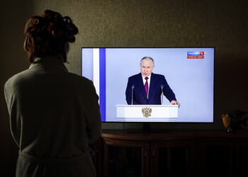 Γυναίκα παρακολουθεί στην τηλεόραση το ετήσιο διάγγελμα του Βλαντίμιρ Πούτιν προς το έθνος (φωτ.: EPA / Yuri Kochetkov)