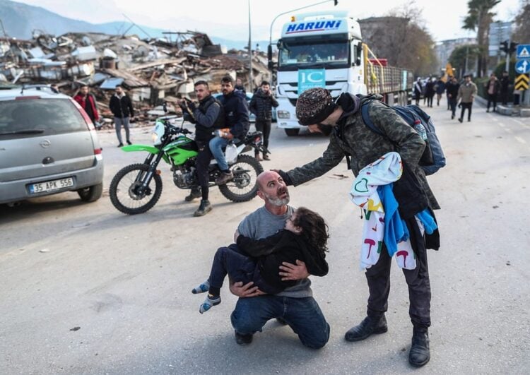 Άνδρας κουβαλά ένα κοριτσάκι που μόλις έχει διασωθεί από ερείπια κτηρίου στο Χατάι (φωτ.: EPA/Erdem Sahin)
