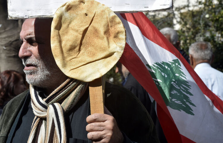 Διαδηλωτής έχει καρφώσει στο πλακάτ λιβανέζικο ψωμί (φωτ.: EPA / Wael Hamzeh)