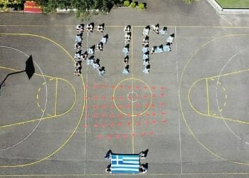 Οι μαθητές άνοιξαν μια μεγάλη ελληνική σημαία και ζωγράφισαν στο δάπεδο 57 ραγισμένες καρδιές, ενώ με τα σώματά τους σχημάτισαν τη συντομογραφία RIP («Rest In Peace», που στα ελληνικά σημαίνει «Αναπαύσου εν ειρήνη») (φωτ.: neoskosmos.com)