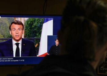 Άνδρας παρακολουθεί στην τηλεόραση σε μπαρ του Παρισιού τον Εμανουέλ Μακρόν να απευθύνει διάγγελμα προς το γαλλικό λαό (φωτ.: EPA/Teresa Suarez)