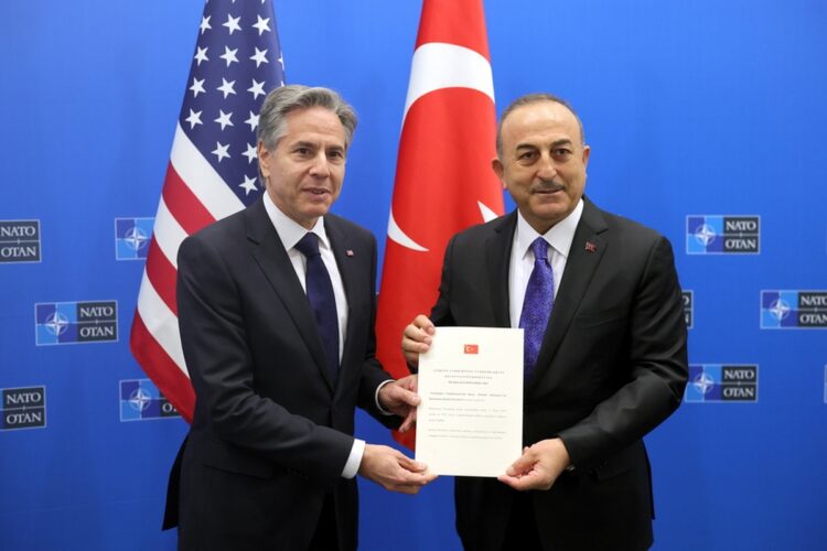 Ο Τούρκος υπουργός Εξωτερικών Μεβλούτ Τσαβούσογλου δίνει στον Αμερικανό ομόλογό του Άντονι Μπλίνκεν το έγγραφο επικύρωσης της προσχώρησης της Φινλανδίας στο ΝΑΤΟ (φωτ.: EPA/Olivier Matthys/POOL)