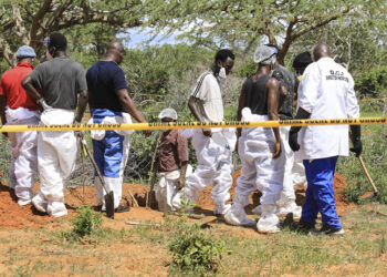 Κενυάτες αστυνομικοί και ειδικοί της σήμανσης πάνω από ρηχό τάφο όπου υπήρχαν νεκρά μέλη της αίρεσης (φωτ.: EPA / STR)