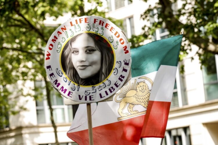 Διαδηλωτής κρατά πανό με τη φωτογραφία της Μαχσά Αμινί στη διάρκεια διαμαρτυρίας μπροστά από την ιρανική πρεσβεία στο Παρίσι (φωτ.: EPA/Teresa Suarez)