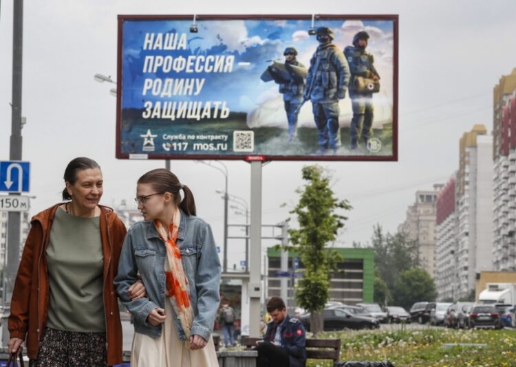 Ρωσίδες στη Μόσχα προσπερνούν αφίσα που ζητά εθελοντές για κατάταξη στο στρατό με το σύνθημα «Επάγγελμά μας η προστασία της πατρίδας» (φωτ.: EPA/Yuri Kochetkov)