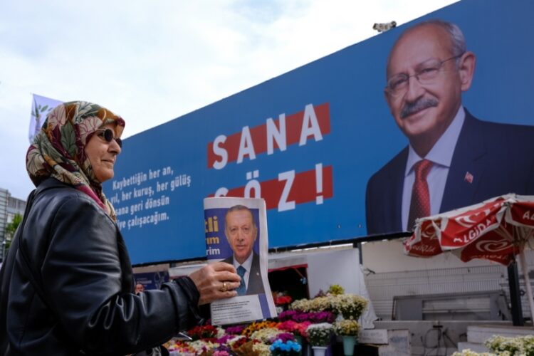 Γυναίκα μοιράζει φυλλάδια του Ρετζέπ Ταγίπ Ερντογάν μπροστά από αφίσα του Κεμάλ Κιλλιτσντάρογλου στην Κωνσταντινούπολη (φωτ.: EPA/Sedat Suna)