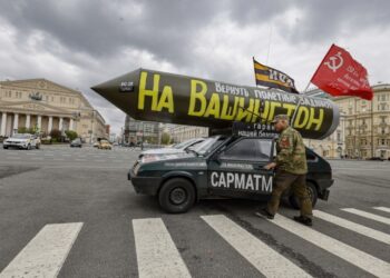 Ένας Ρώσος μπαίνει στο αυτοκίνητό του, το οποίο έχει τοποθετημένο στην οροφή έναν ψεύτικο ρωσικό πύραυλο «Sarmat», τη σημαία της Σοβιετικής Ένωσης και την επιγραφή στα ρωσικά «Ας επιστρέψουμε τις αποστολές πτήσης για πυραύλους στην Ουάσιγκτον», με αφορμή τους εορτασμούς της Πρωτομαγιάς στο κέντρο της Μόσχας (φωτ.: EPA/Sergei Ilnitsky)