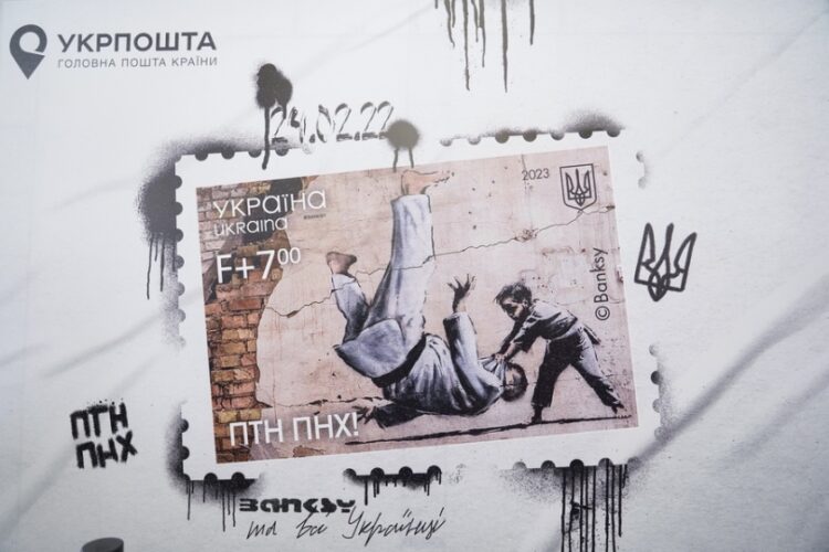 Γραμματόσημο των Ουκρανικών Ταχυδρομείων φιλοξενεί την τοιχογραφία του Βρετανού καλλιτέχνη Μπάνκσι, στην οποία απεικονίζεται ένα μικρό παιδί να ρίχνει κάτω έναν άνδρα, που μοιάζει με τον Βλαντίμιρ Πούτιν, με μια κίνηση τζούντο. Το συγκεκριμένο γκράφιτι είχε εμφανιστεί στον τοίχο κατεστραμμένου από ρωσικό βομβαρδισμό σπιτιού, σε χωριό κοντά στο Κίεβο (φωτ.: EPA/Oleg Pereverzev)