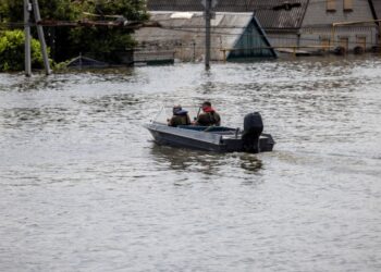 Κάτοικοι και διασώστες κινούνται με βάρκα σε πλημμυρισμένη περιοχή στη Χερσώνα (φωτ.: EPA/Stas Kozliuk)