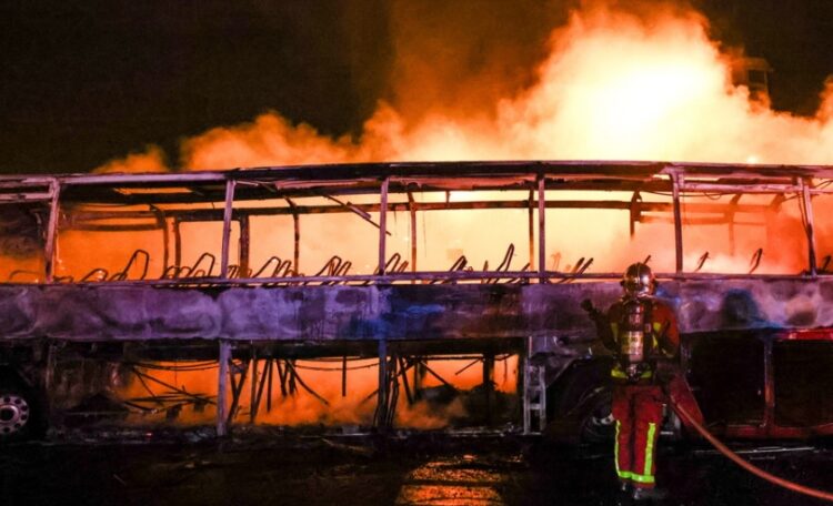 Πυροσβέστης προσπαθεί να κατασβέσει πυρκαγιά σε φλεγόμενο λεωφορείο στη Ναντέρ (φωτ.: EPA/Mohammed Badra)
