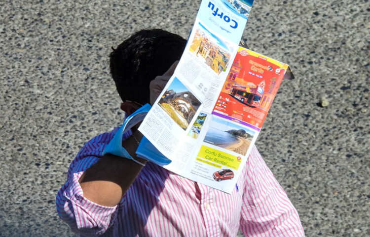 Τουρίστας προστατεύει το κεφάλι του από τη ζέστη με έναν χάρτη της Κέρκυρας (φωτ.: EUROKINISSI / Γιώργος Κονταρίνης)