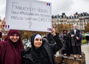 Μουσουλμάνες ντυμένες με αμπάγια κρατούν πανό που αναγράφει «Γαλλίδες και καλυμμένες, κάνουμε τα καθήκοντά μας, που είναι τα δικαιώματά μας;» στη διάρκεια διαμαρτυρίας στο Παρίσι (φωτ.: EPA/Christophe Petit Tesson)
