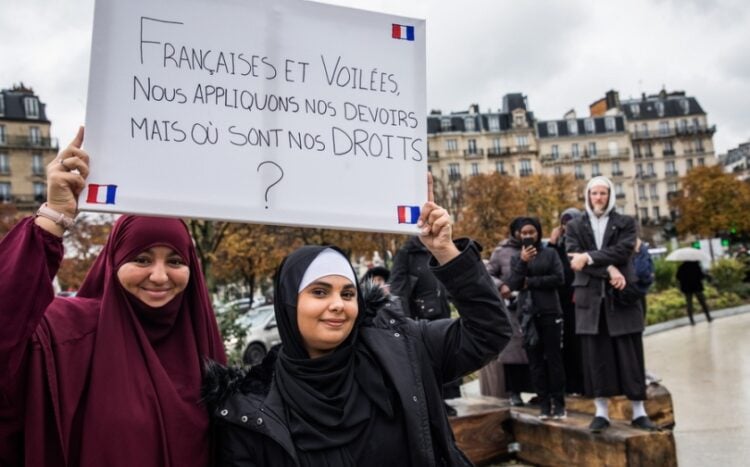 Μουσουλμάνες ντυμένες με αμπάγια κρατούν πανό που αναγράφει «Γαλλίδες και καλυμμένες, κάνουμε τα καθήκοντά μας, που είναι τα δικαιώματά μας;» στη διάρκεια διαμαρτυρίας στο Παρίσι (φωτ.: EPA/Christophe Petit Tesson)