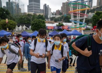 Μικροί μαθητές στο Χονγκ Κονγκ περπατούν κοιτώντας τα κινητά τους τηλέφωνα (φωτ.: EPA/Jerome Favre)