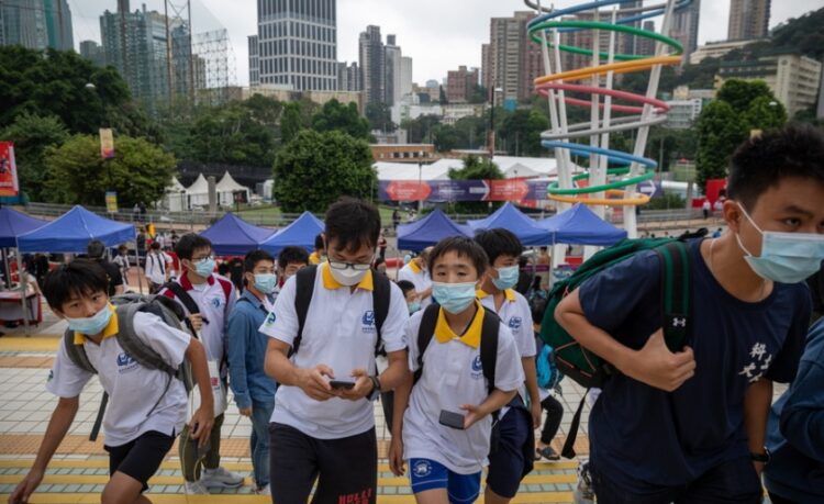 Μικροί μαθητές στο Χονγκ Κονγκ περπατούν κοιτώντας τα κινητά τους τηλέφωνα (φωτ.: EPA/Jerome Favre)