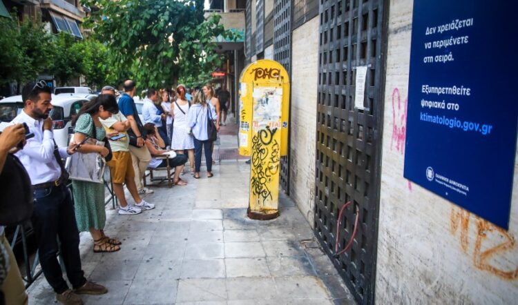 Πολίτες περιμένουν στην ουρά για να εξυπηρετηθούν στο κτηματολογικό γραφείο της Αθήνας, υπό την ανακοίνωση για τις νέες ψηφιακές υπηρεσίες (φωτ.: EUROKINISSI/Γιάννης Παναγόπουλος)