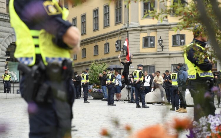 Σουηδοί αστυνομικοί φρουρούν ομάδα μουσουλμάνων που διαμαρτύρεται για το κάψιμο του Κορανίου σε πλατεία της Στοκχόλμης (φωτ.: EPA/Oscar Olsson)