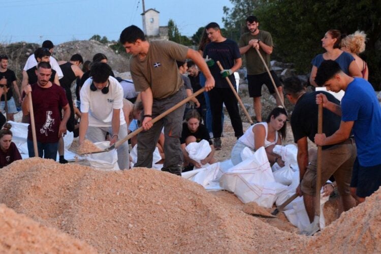 Πλήθος εθελοντών Λαρισαίων, στην πλειοψηφία τους νεαρά παιδιά, γεμίζουν και μεταφέρουν τσουβάλια με άμμο, βοηθώντας τους εργαζόμενους στο δημοτικό φυτώριο Λάρισας, για την ενίσχυση των αναχωμάτων του Πηνειού ποταμού, (φωτ.: ΑΠΕ-ΜΠΕ/Αποστόλης Ντομαλης)