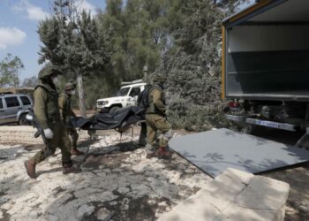 Ισραηλινοί στρατιώτες μεταφέρουν σορούς ομοεθνών τους που σκοτώθηκαν στο κιμπούτζ Κφαρ Αζά, στα σύνορα με τη Γάζα (φωτ.: EPA/ ATEF SAFADI)